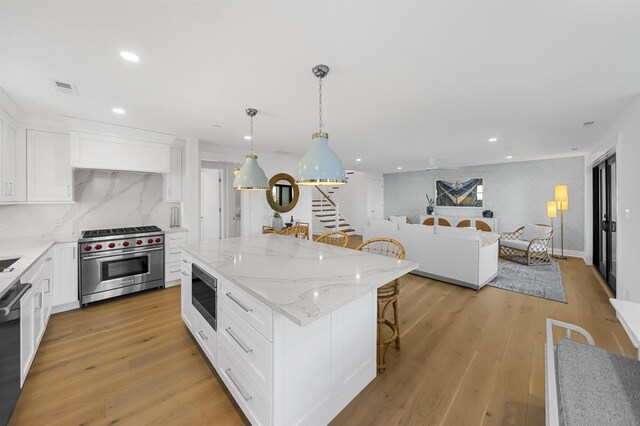 kitchen featuring a kitchen bar, luxury range, white cabinets, a center island, and hanging light fixtures