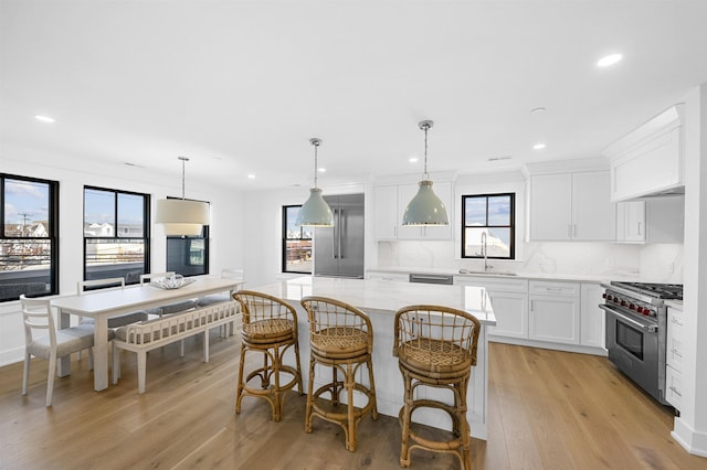 kitchen featuring a center island, white cabinets, sink, appliances with stainless steel finishes, and decorative light fixtures