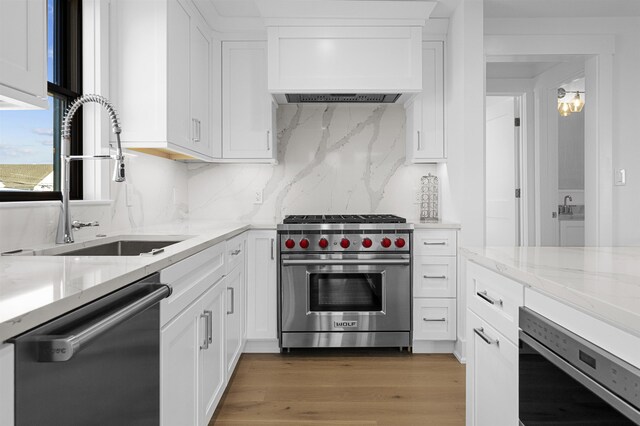 kitchen with white cabinets, stainless steel appliances, premium range hood, and sink