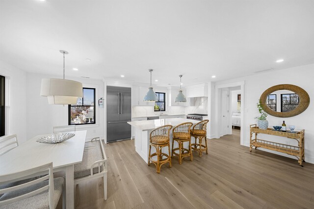 kitchen featuring decorative backsplash, stainless steel built in refrigerator, decorative light fixtures, white cabinets, and a center island