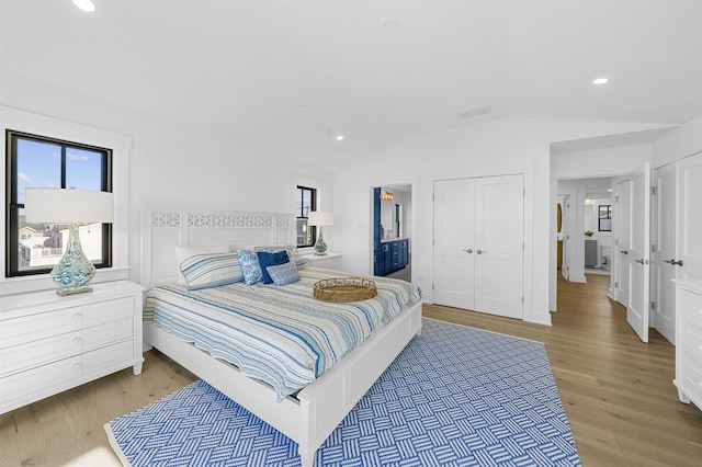 bedroom with a closet, hardwood / wood-style floors, and vaulted ceiling