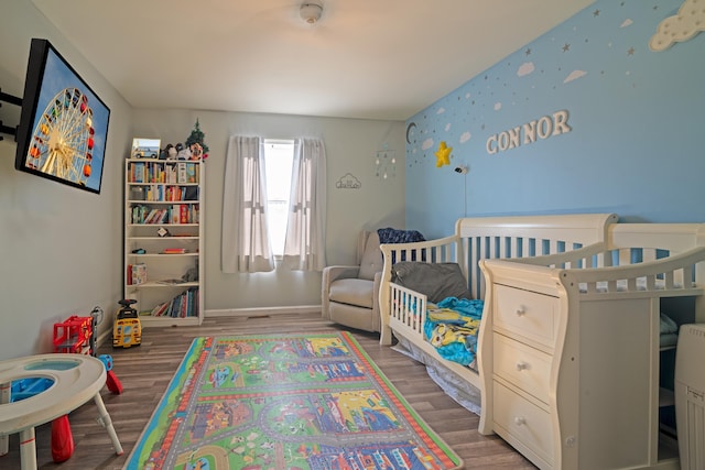 bedroom with a crib and hardwood / wood-style flooring