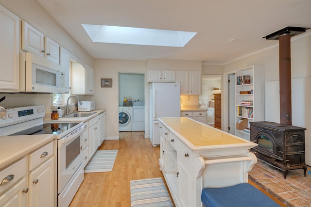 717 Third Ave, West Cape May, NJ 08204 - kitchen featuring white appliances, a skylight, washer and clothes dryer, and a wood stove