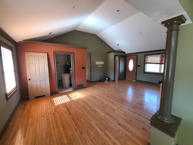 unfurnished living room with decorative columns, plenty of natural light, light hardwood / wood-style floors, and vaulted ceiling