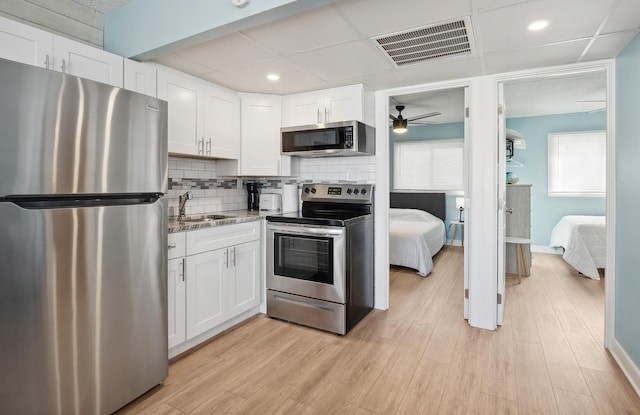 kitchen with appliances with stainless steel finishes, backsplash, visible vents, and white cabinets