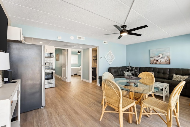dining space featuring light wood-type flooring, ceiling fan, and visible vents