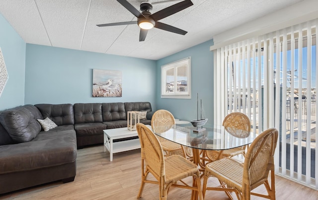 dining space featuring light wood-type flooring, ceiling fan, and a textured ceiling