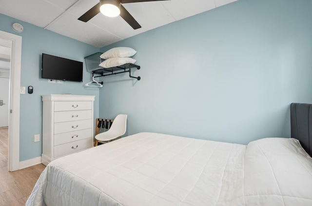 bedroom with wood finished floors, a ceiling fan, and baseboards