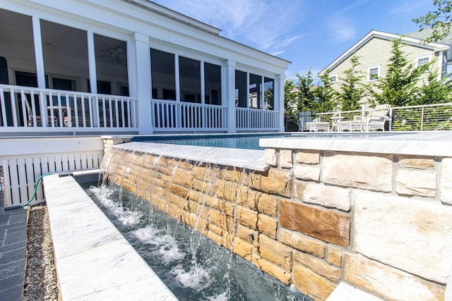 view of swimming pool featuring pool water feature and a sunroom