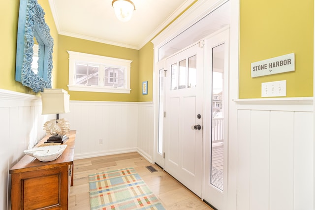 entrance foyer featuring crown molding, a healthy amount of sunlight, and light wood-type flooring