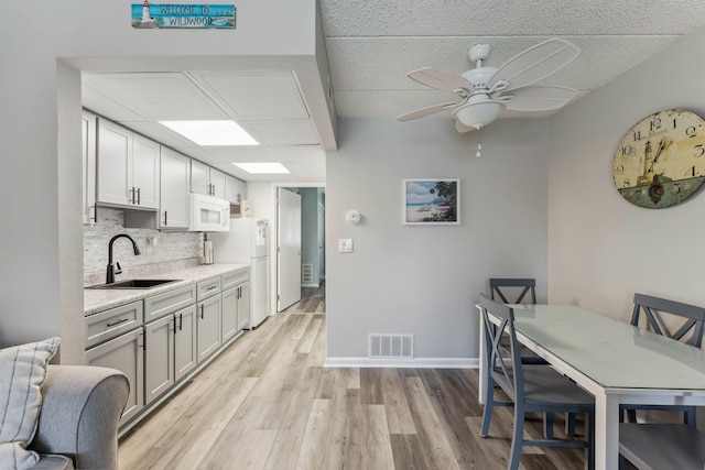 417 E 22nd Ave Unit 101, North Wildwood, NJ 08260 - kitchen with white appliances, light wood-style floors, light countertops, a ceiling fan, and decorative backsplash