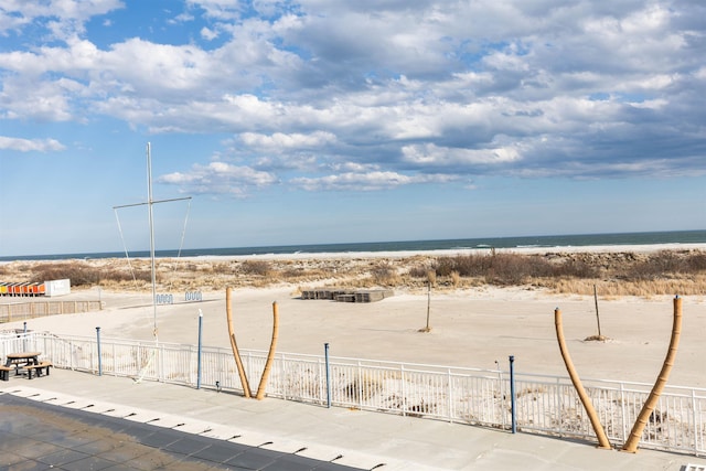 property view of water featuring fence and a view of the beach