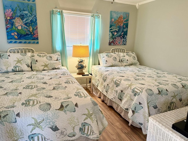 bedroom featuring ornamental molding and wood finished floors