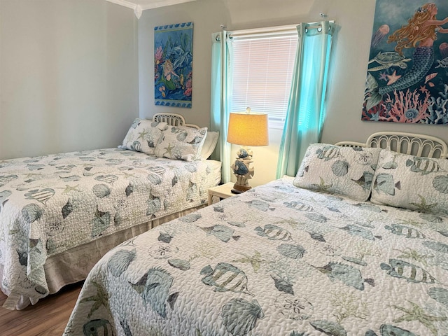 bedroom with ornamental molding and wood finished floors