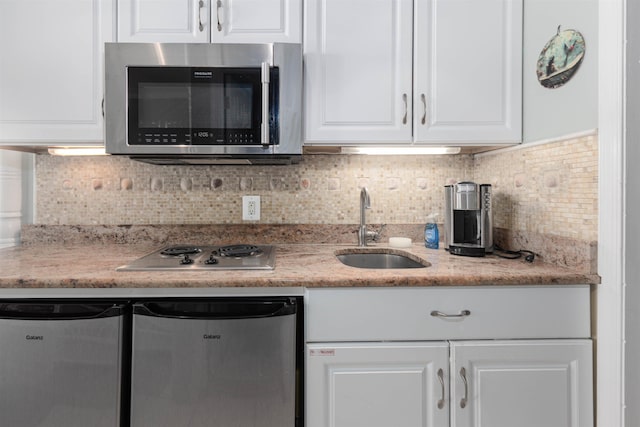 kitchen with white cabinets, backsplash, stainless steel appliances, and a sink