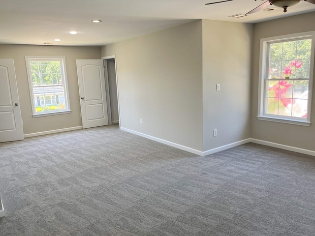 spare room featuring ceiling fan, plenty of natural light, and light colored carpet