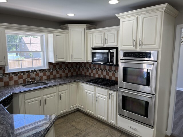 kitchen featuring white cabinets, backsplash, stainless steel appliances, and sink