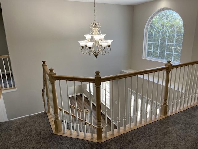 stairway featuring carpet floors and a chandelier