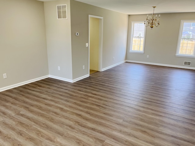 unfurnished room featuring hardwood / wood-style floors and a chandelier