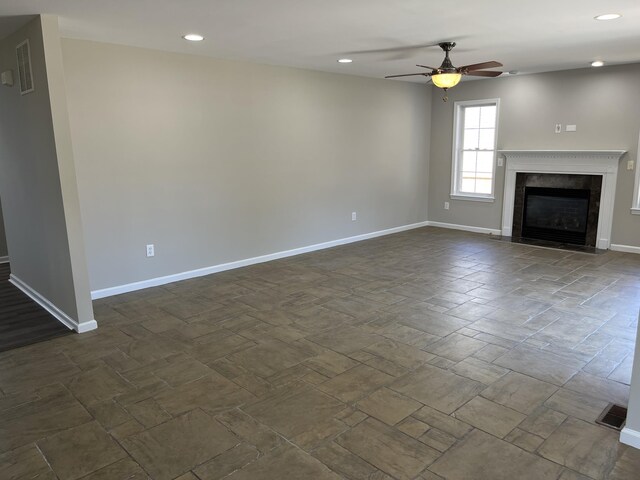 unfurnished living room with a premium fireplace and ceiling fan