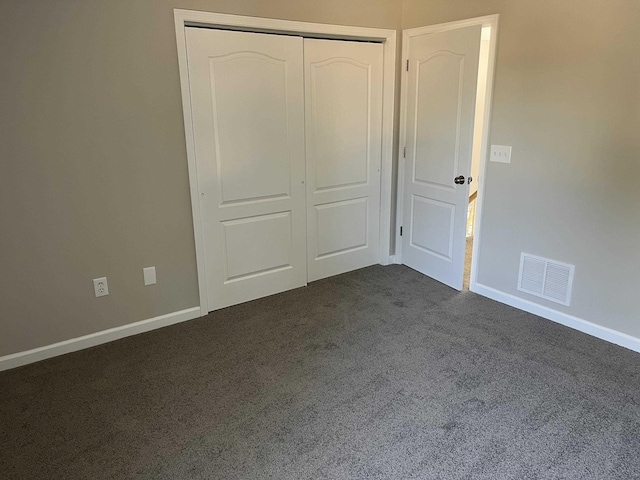 unfurnished bedroom featuring dark colored carpet and a closet