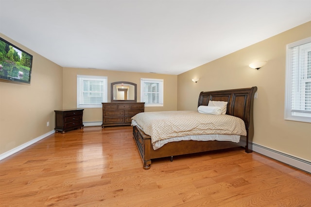 bedroom with light hardwood / wood-style floors, a baseboard radiator, and multiple windows