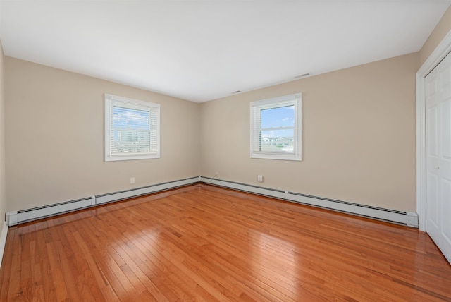 empty room featuring light wood-type flooring and a baseboard radiator