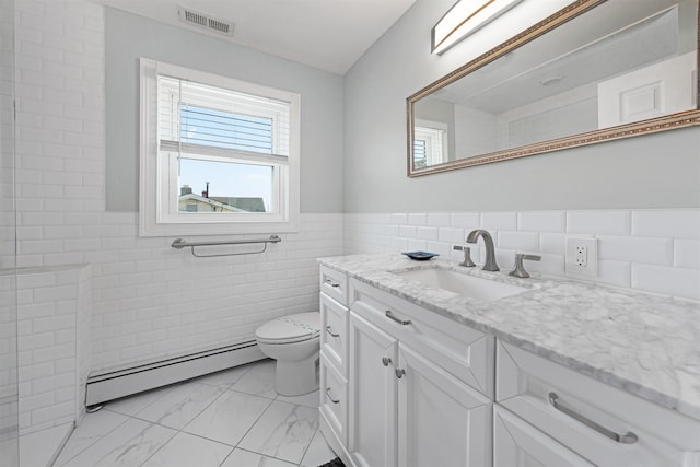 bathroom featuring vanity, toilet, baseboard heating, and tile walls