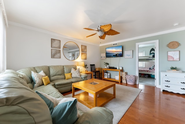 living area featuring dark wood-type flooring, ceiling fan, and crown molding