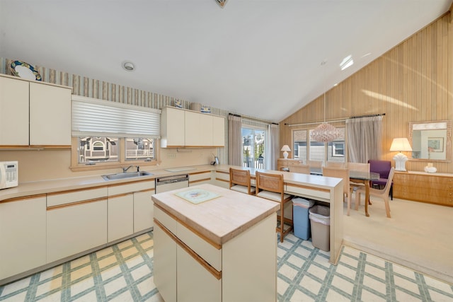 kitchen featuring white microwave, dishwashing machine, wood walls, and a sink