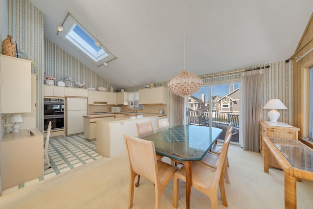 dining area with wallpapered walls, a skylight, light colored carpet, and high vaulted ceiling