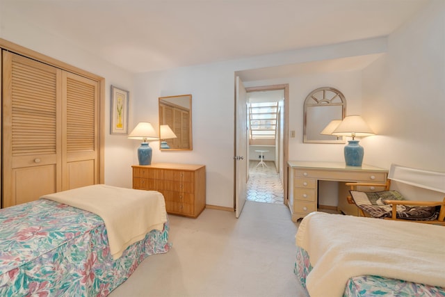 bedroom featuring light colored carpet, a closet, and baseboards