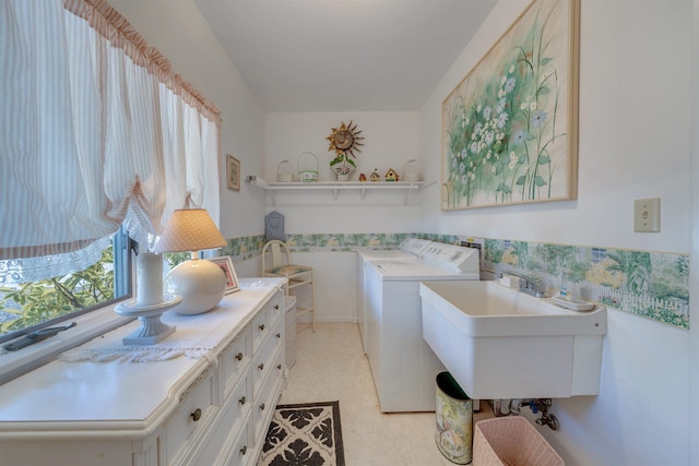 washroom featuring a sink, washing machine and dryer, cabinet space, wainscoting, and light floors