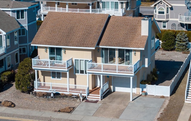 view of front of home featuring fence, driveway, roof with shingles, a porch, and a chimney