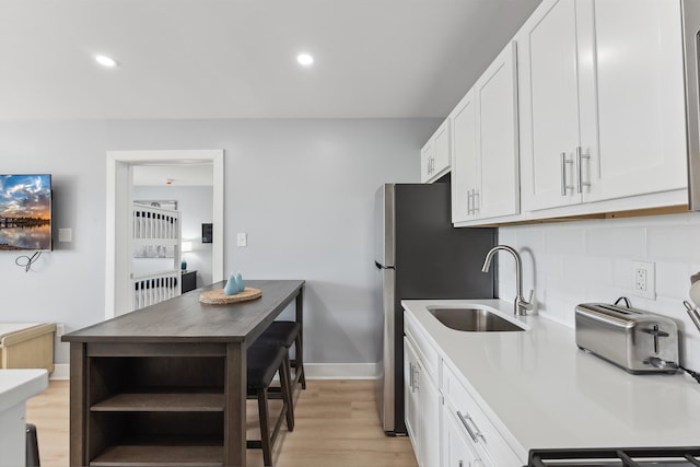 kitchen with white cabinetry, sink, tasteful backsplash, and light hardwood / wood-style flooring