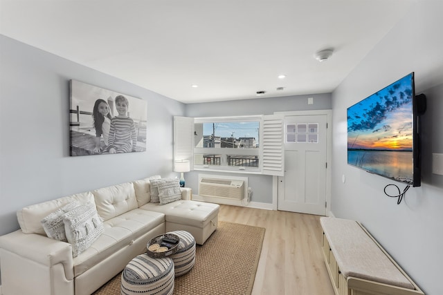 living room featuring a wall mounted AC and light hardwood / wood-style floors