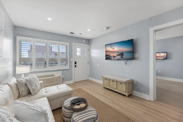 living room with an AC wall unit and light wood-type flooring