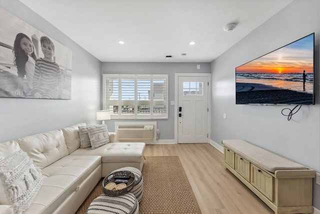 living room with light hardwood / wood-style floors and a wall unit AC