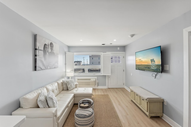 living room with a wall mounted air conditioner and light hardwood / wood-style floors