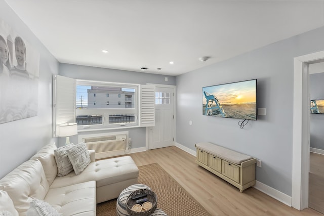 living room with a wall unit AC and light hardwood / wood-style flooring