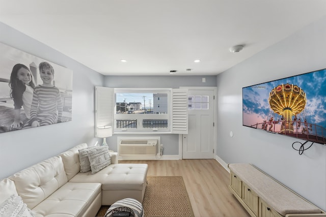 living room featuring a wall mounted air conditioner and light hardwood / wood-style floors