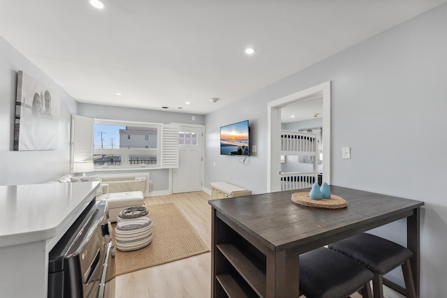 dining space with a wall mounted AC and light hardwood / wood-style floors