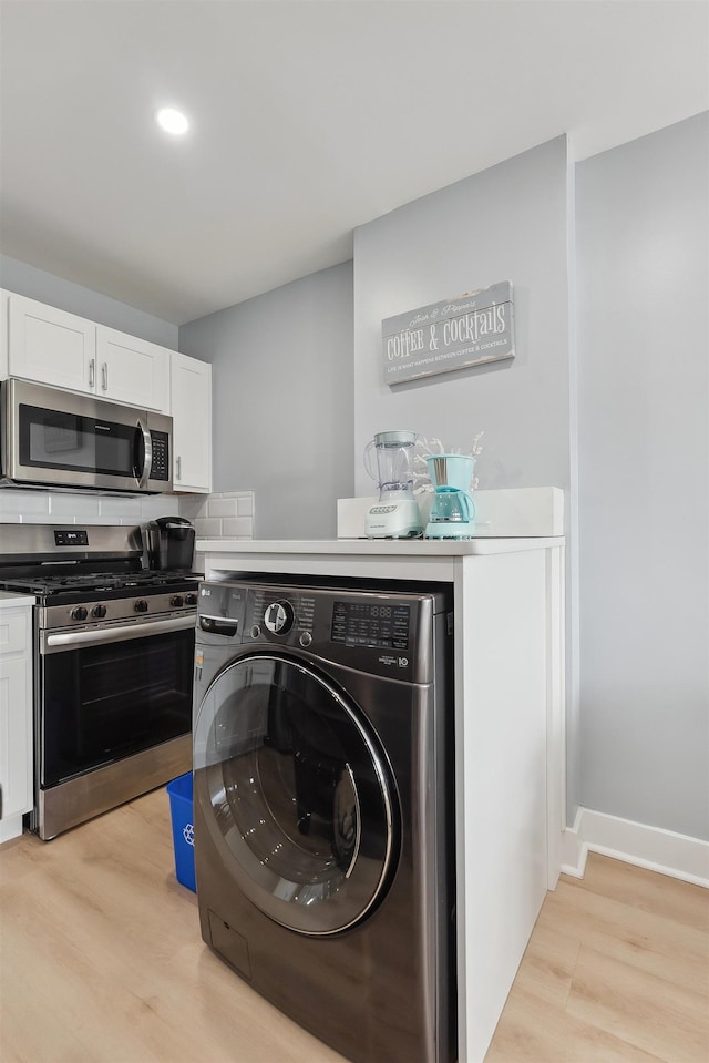 laundry room with washer / dryer and light wood-type flooring