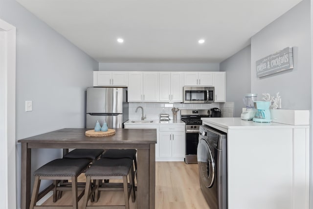 kitchen featuring tasteful backsplash, washer / dryer, sink, white cabinets, and stainless steel appliances