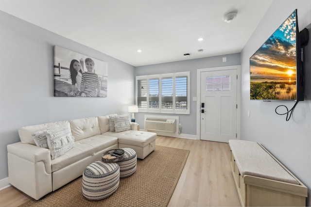 living room with a wall mounted AC and light hardwood / wood-style floors