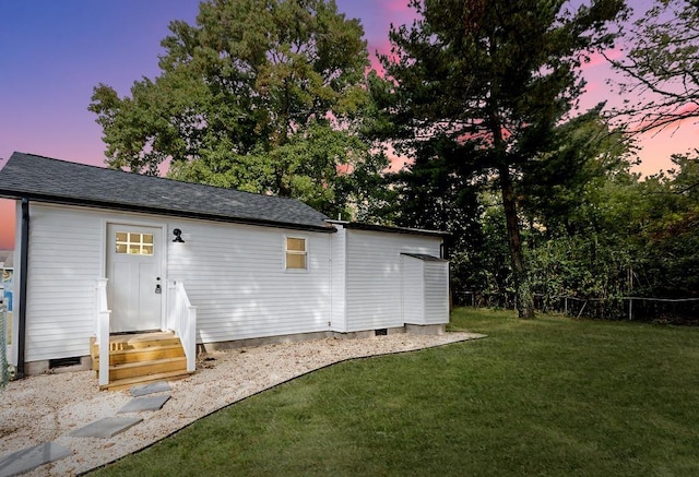 back house at dusk featuring a yard