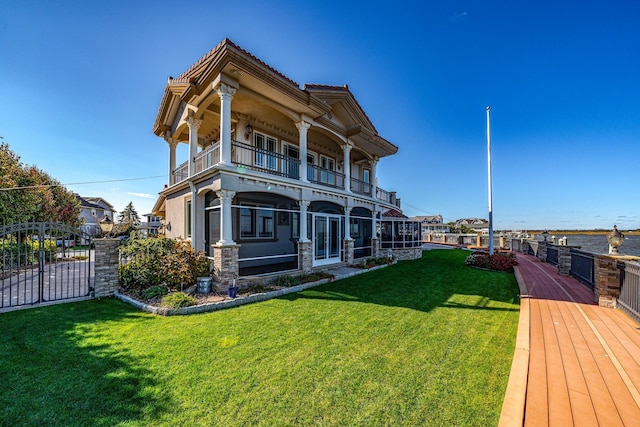 rear view of property with a balcony and a yard