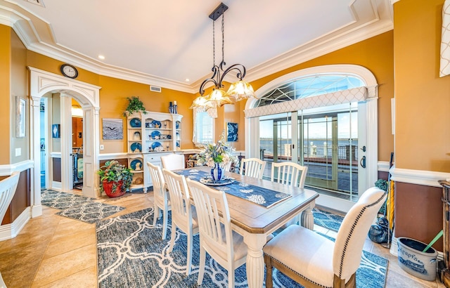 dining space featuring tile patterned floors, crown molding, and an inviting chandelier