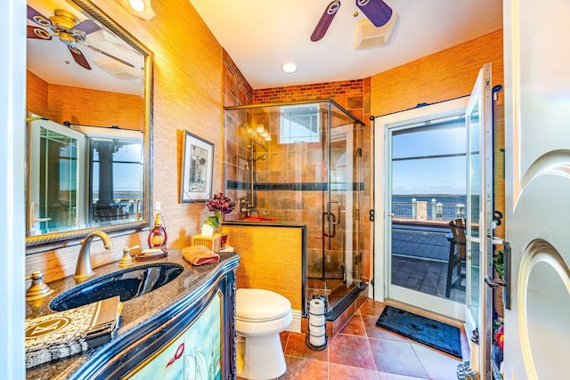 bathroom with vanity, a shower with door, tile patterned flooring, ceiling fan, and toilet