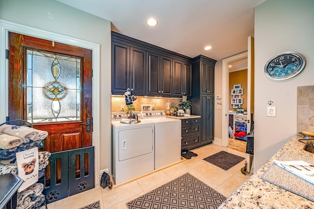 clothes washing area featuring separate washer and dryer, light tile patterned floors, and cabinets